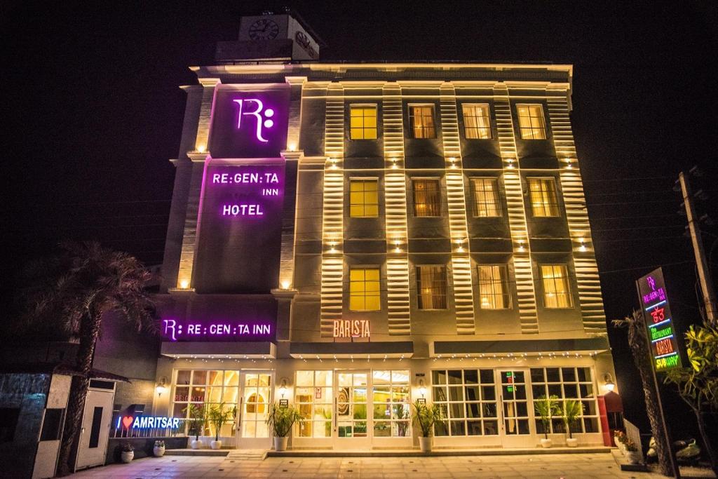 duży budynek z fioletowymi znakami w nocy w obiekcie Regenta Inn Amristar Airport Road by Royal Orchid Hotels Limited w mieście Amritsar