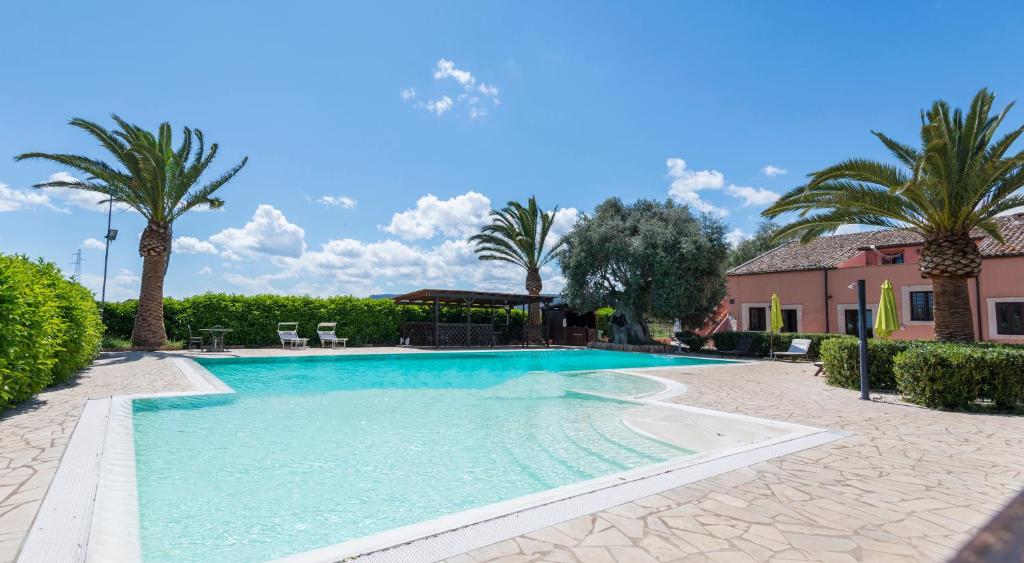einen Pool mit Palmen und ein Haus in der Unterkunft Hotel Lady Lusya in Syrakus