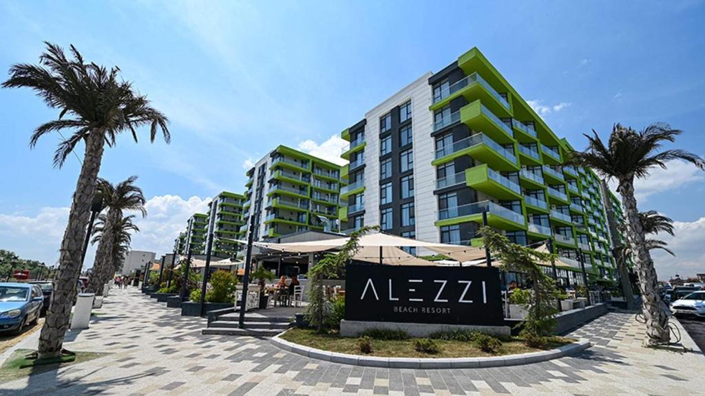 ein großes Gebäude mit Palmen davor in der Unterkunft GreenView Alezzi Beach Resort in Mamaia Nord – Năvodari