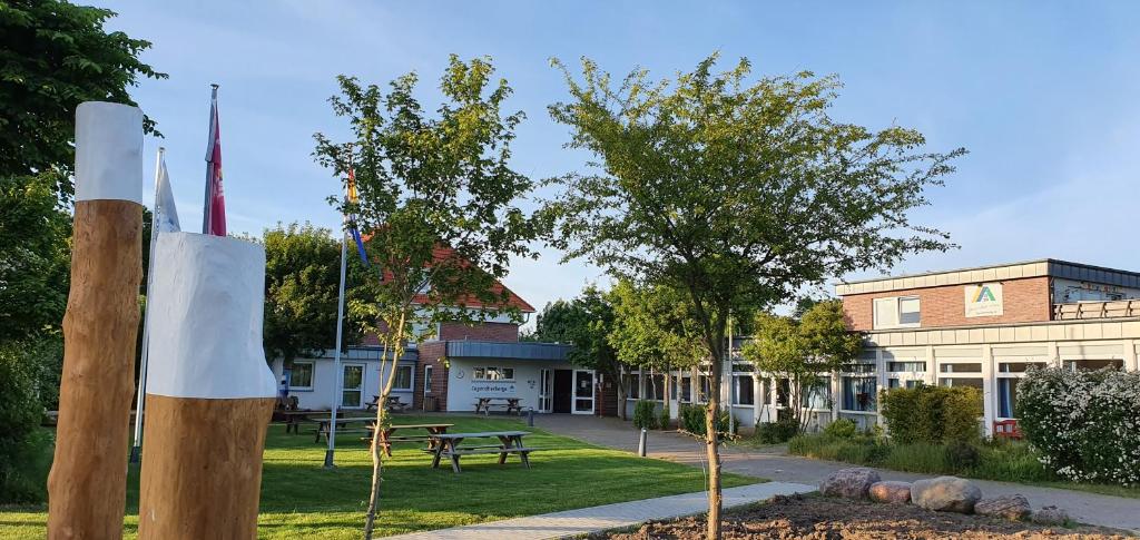 a building with a park with a bench and trees at Jugendherberge Fehmarn in Fehmarn