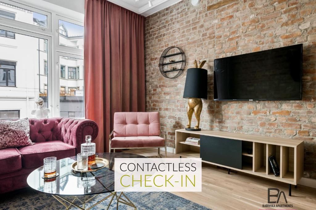 a living room with a couch and a tv on a brick wall at BJØRVIKA APARTMENTS - Solli in Oslo