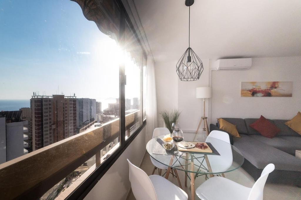 sala de estar con mesa y sillas y balcón en Moonkey - Luminoso Apartamento Girasoles, en Benidorm