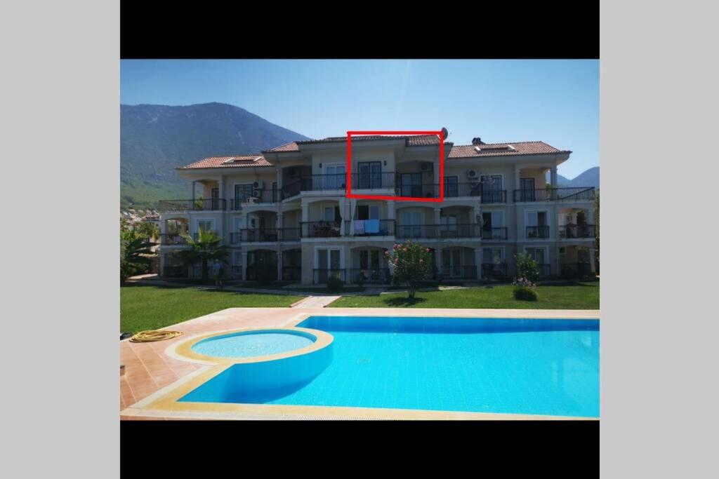 a large house with a swimming pool in front of it at Ölüdenizde lüx havuzlu daire in Fethiye
