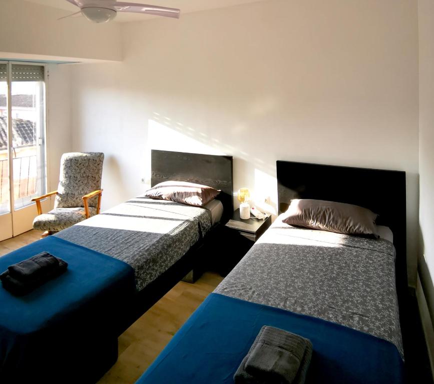 1 dormitorio con 2 camas y 1 silla en Piso De Balboa Wi-Fi, Air-Con, en Gandía