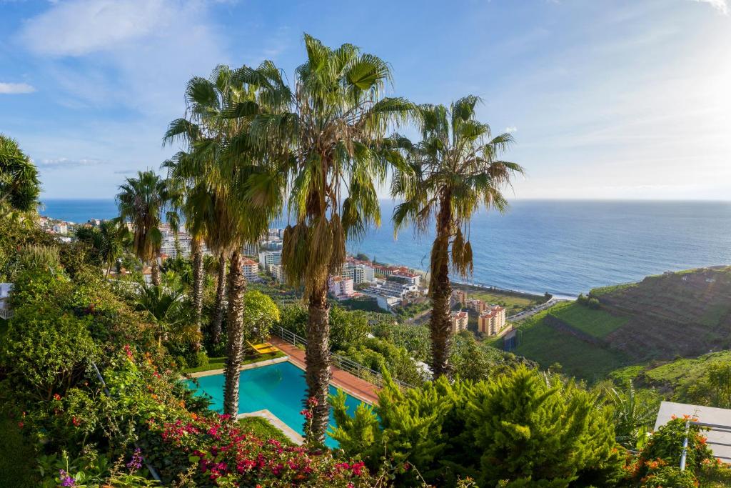 Blick auf ein Resort mit Palmen und das Meer in der Unterkunft Casa do Papagaio Verde in Funchal