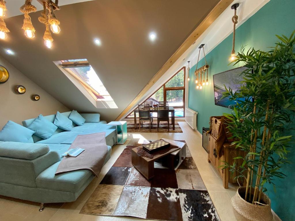 uma sala de estar com um sofá azul e uma clarabóia em Kalinderu Ski Loft em Buşteni