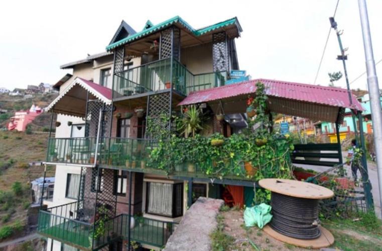 a large house with a balcony and a wheel in front of it at Kasauli Residency in Kasauli