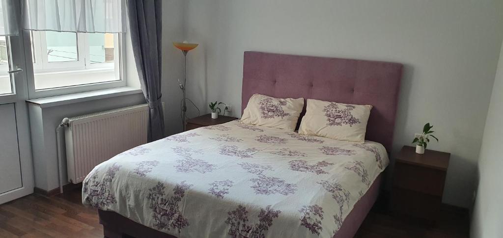 een slaapkamer met een bed met een paars en wit dekbed bij D&Y Apartments in Piatra Neamţ