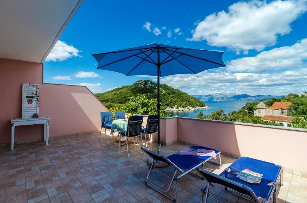 eine Terrasse mit einem Tisch, Stühlen und einem Sonnenschirm in der Unterkunft Apartment Bay of Dreams in Janjina