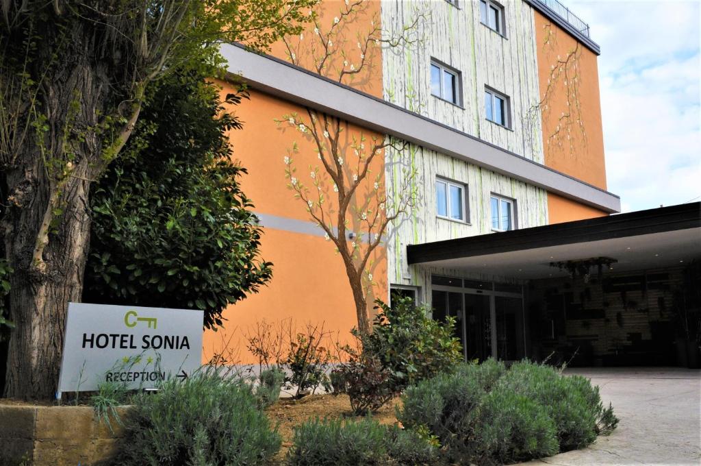 un bâtiment orange avec un panneau devant lui dans l'établissement Hotel Sonia, à Trieste