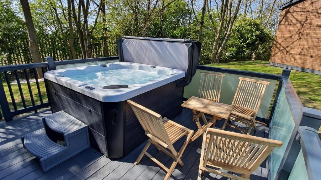 a hot tub on a deck with two chairs and a table at Biarritz Lodge in Hull