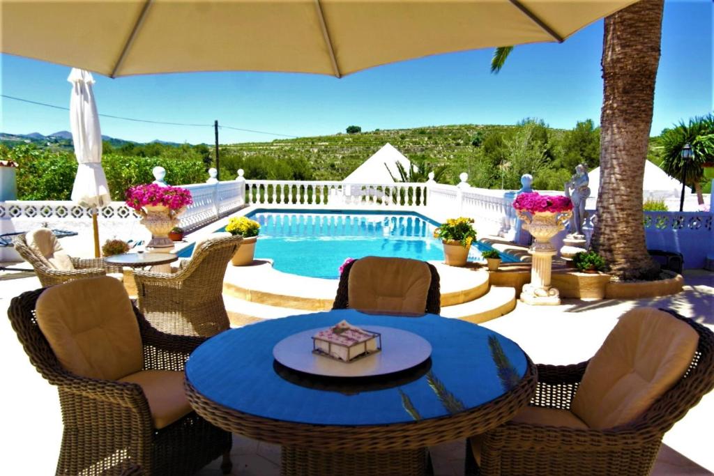 eine Terrasse mit einem Tisch, Stühlen und einem Pool in der Unterkunft Treasurita Guest House in Moraira