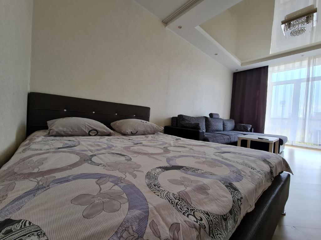 a bedroom with a large bed and a couch at Апартаменты на площади Ленина от ApartmentCity in Mogilev