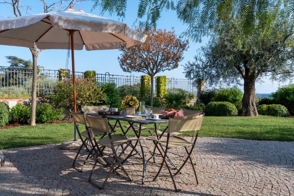 stół i dwa krzesła pod parasolem w obiekcie Villa Rosmarino w mieście Imperia