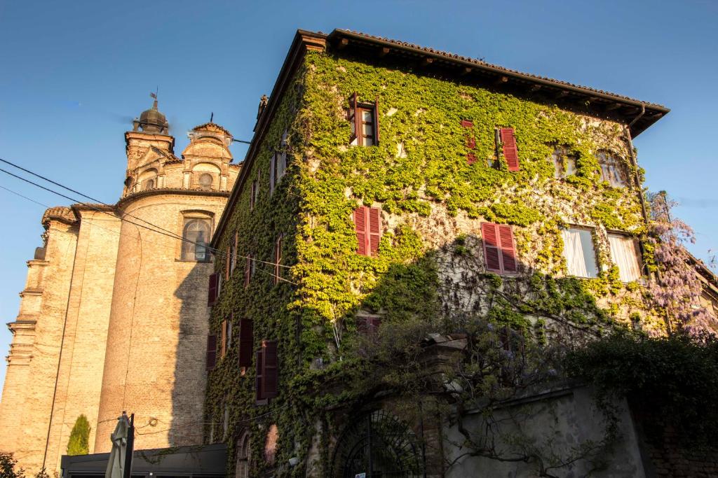 um edifício coberto de hera ao lado de uma torre em L'Aromatario em Neive