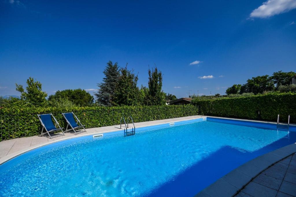 uma piscina com duas cadeiras azuis ao lado de uma cerca em Groppello em Polpenazze del Garda