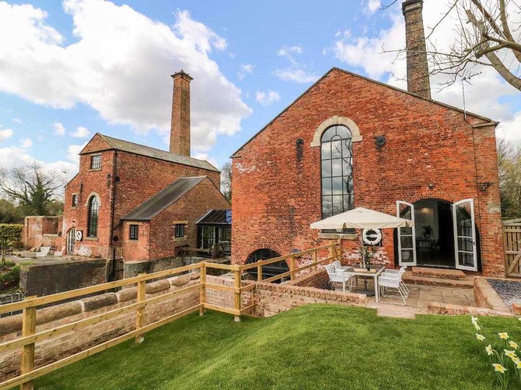 een oud bakstenen gebouw met een tafel en een paraplu bij The Pump House Art Studio in Gainsborough