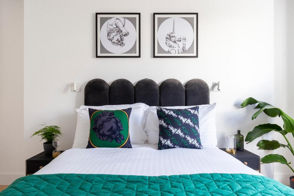a bedroom with a green and white bed with four pictures on the wall at Bloomsbury By Viridian Apartments in London