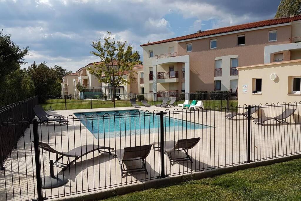une clôture avec des chaises et une piscine en face d'un bâtiment dans l'établissement Charmant studio avec piscine et clim (en été), à Aix-en-Provence