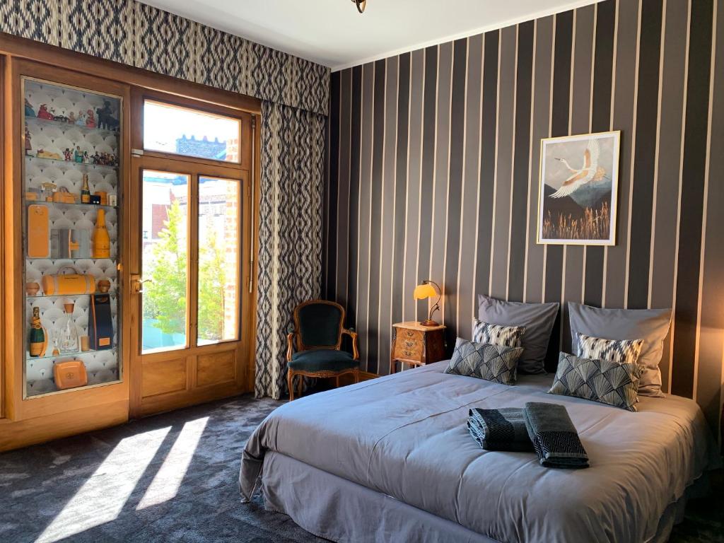 a bedroom with a bed with a striped wall at Maison Longuevie in Amiens