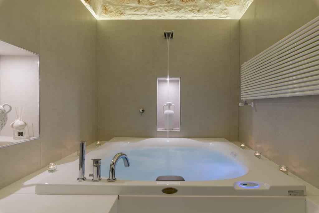 y baño con bañera grande con lámpara. en Pregiata Suite 25, en Ostuni