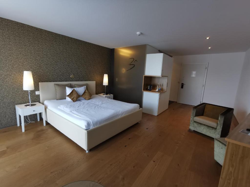 a bedroom with a large white bed and a chair at Hotel AVA in Sempach Station