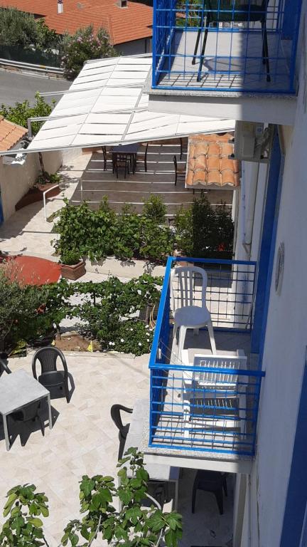 a building with blue balconies and tables and chairs at Hotel Conca d'Oro in Stalettì