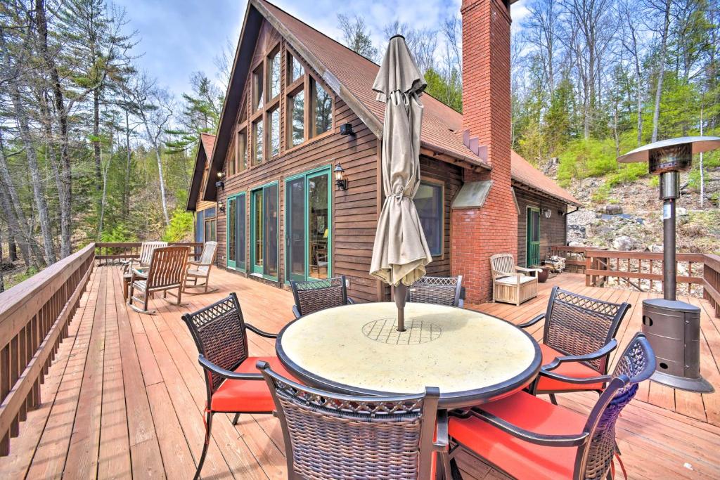 un patio con una mesa con sillas y una sombrilla en Adirondack Oasis Lake House with Dock and Deck!, en Schroon Lake