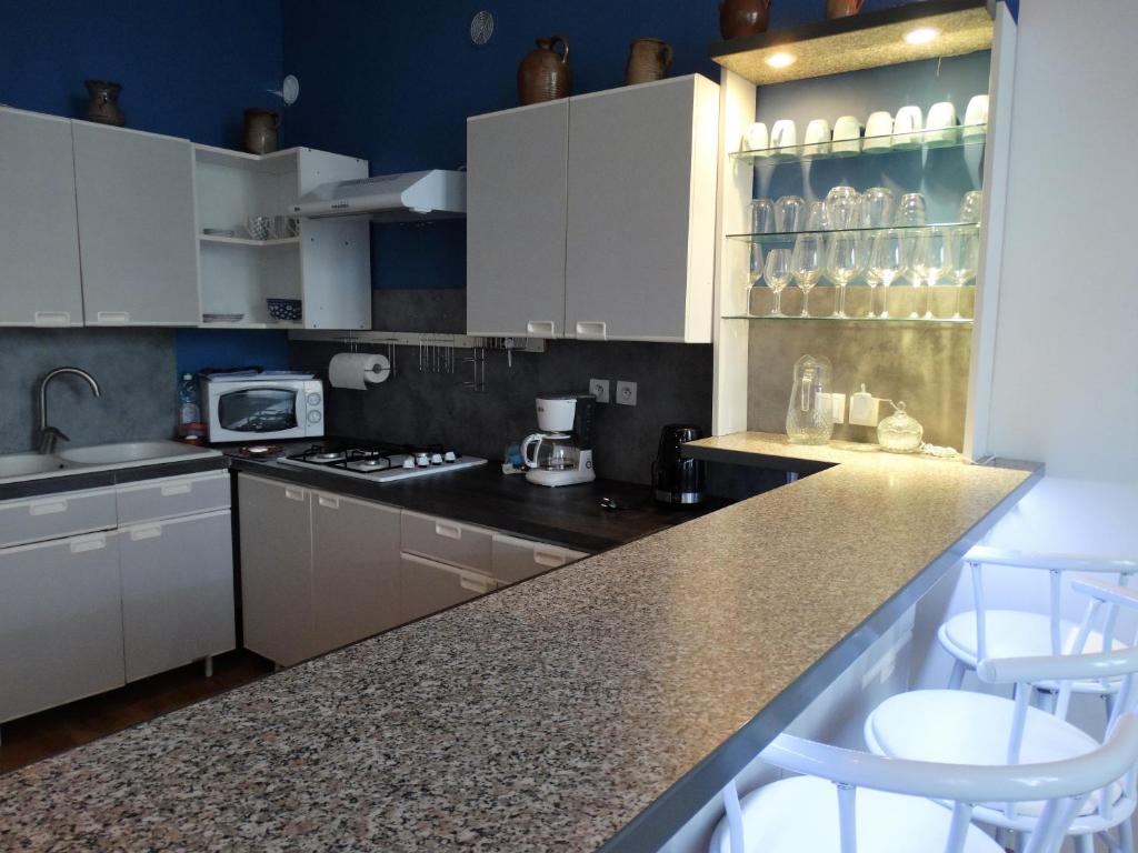 een keuken met witte kasten en een aanrecht met krukken bij Location courte durée in Saumur