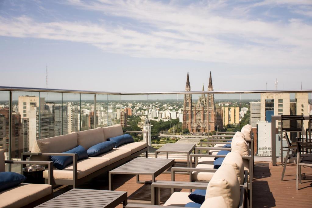 a balcony with couches and tables and a view of a city at Grand Brizo La Plata in La Plata