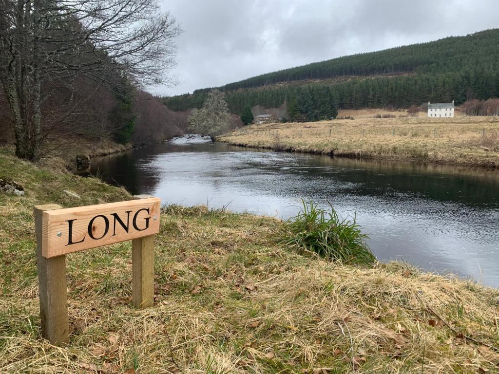 a sign that reads long next to a river at Knocklea in Alness