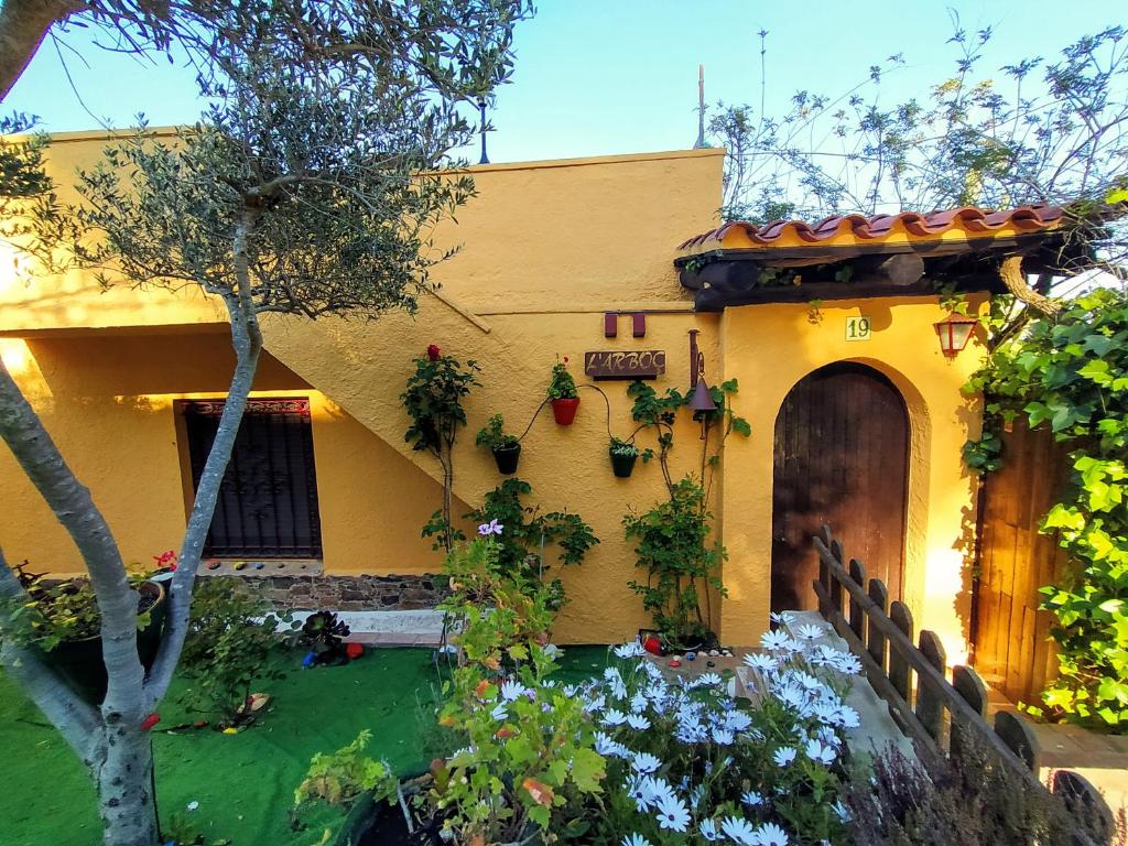 een geel huis met een tuin ervoor bij L´ARBOÇ in Vall-Llobrega