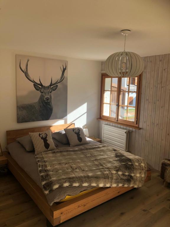 Schlafzimmer mit einem Bett mit einem Hirschbild an der Wand in der Unterkunft Le Cerf, magnifique studio avec jardin-terrasse et garage in Evolène