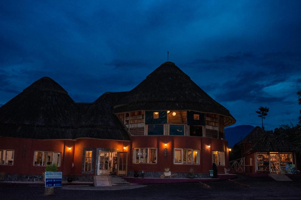 a large building with a thatched roof at night at Ingagi Park View Lodge in Kinigi