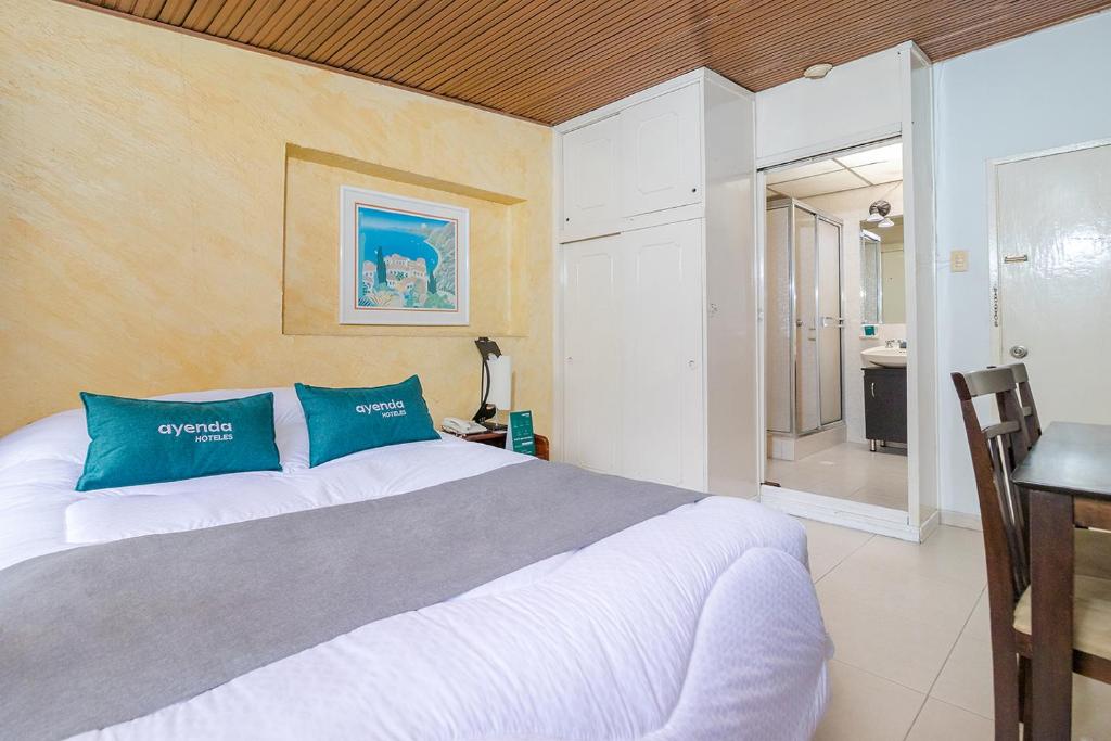 ein Schlafzimmer mit einem großen Bett mit blauen Kissen in der Unterkunft Ayenda Calle 112 1050 in Bogotá