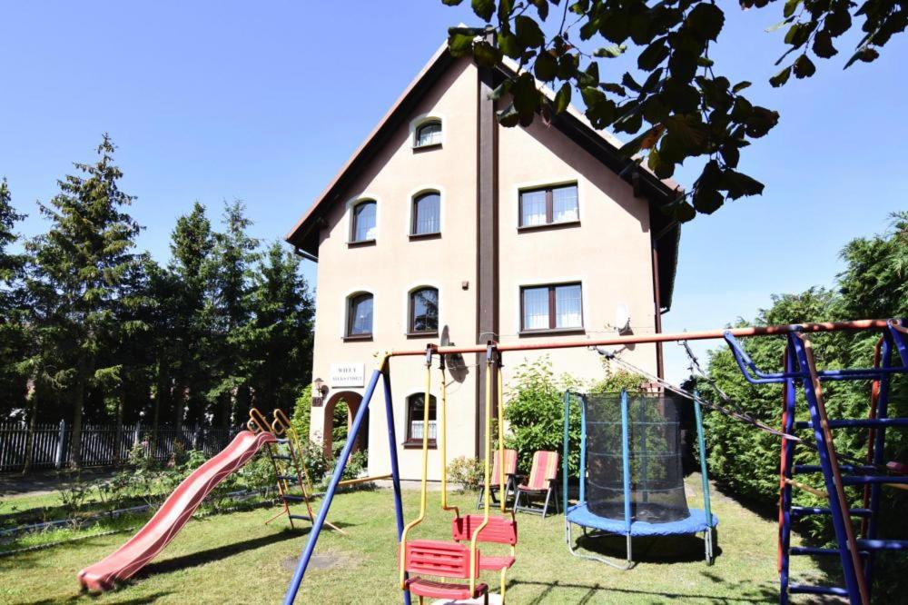 une maison avec une aire de jeux en face d'une maison dans l'établissement Willa Aleksandra, à Żarnowska