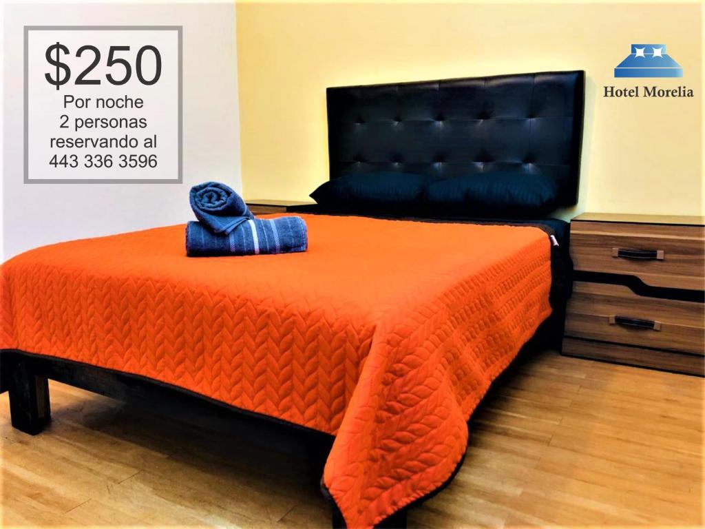 1 cama con edredón naranja y manta azul en Hotel Morelia In en Morelia