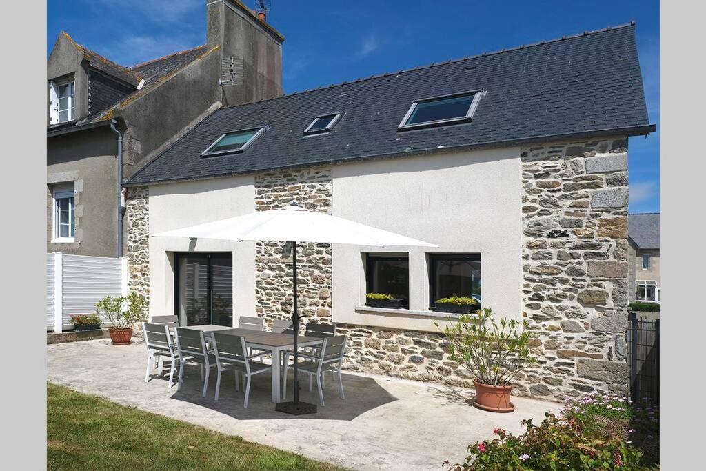 einem Tisch mit Stühlen und einem Regenschirm vor einem Gebäude in der Unterkunft Maison près de la plage et de la thalasso in Roscoff