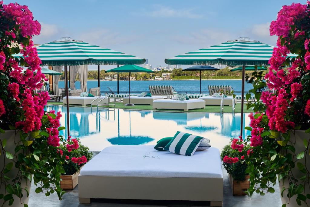 a pool with a bed and some chairs and flowers at Mondrian South Beach in Miami Beach