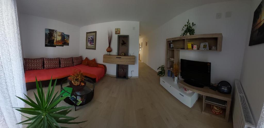a living room with a red couch and a flat screen tv at Apartman Šarm Srebrno jezero in Veliko Gradište