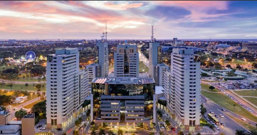 un perfil urbano con altos edificios blancos y coches en Apartamento no condomínio do Brasil 21 Suites en Brasilia