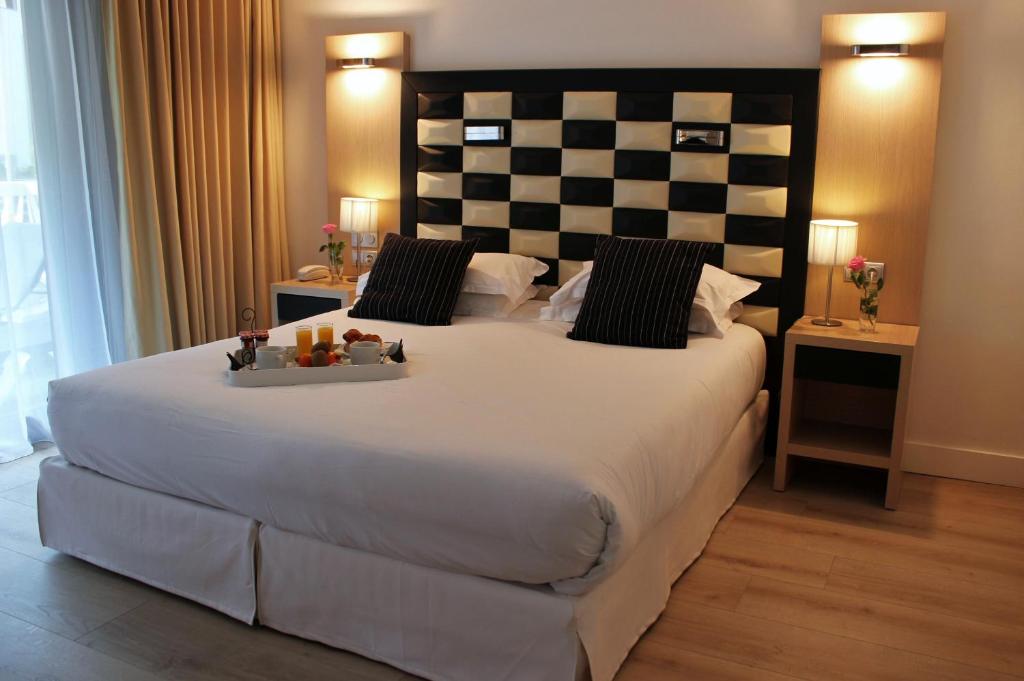 a bedroom with a large bed with a checkered headboard at Hôtel Victoria in Cannes