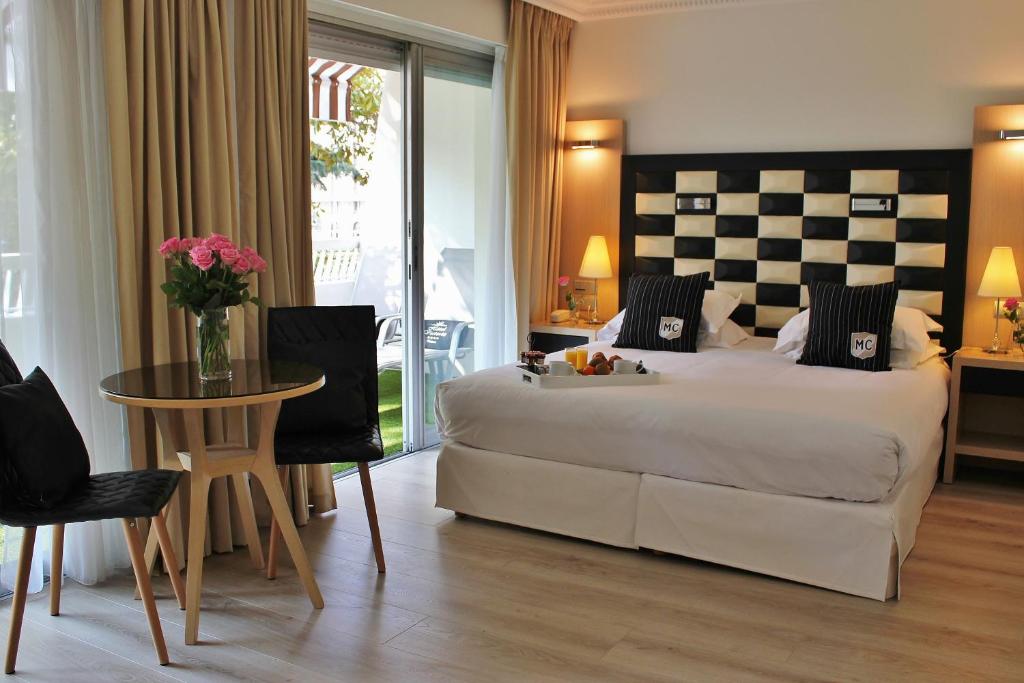 a bedroom with a large bed and a table and chairs at Hôtel Victoria in Cannes