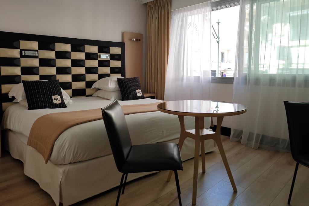 a hotel room with a bed and a table and chairs at Hôtel Victoria in Cannes