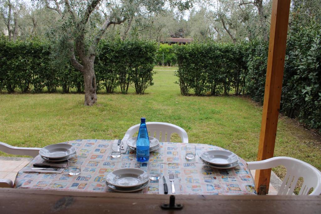- une table avec des assiettes et une bouteille bleue au-dessus dans l'établissement Agriturismo Lu Podere, à Alimini