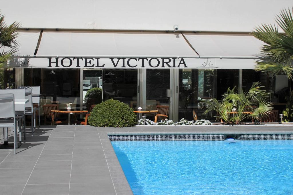 a hotel with a swimming pool in front of a hotel victoria at Hôtel Victoria in Cannes