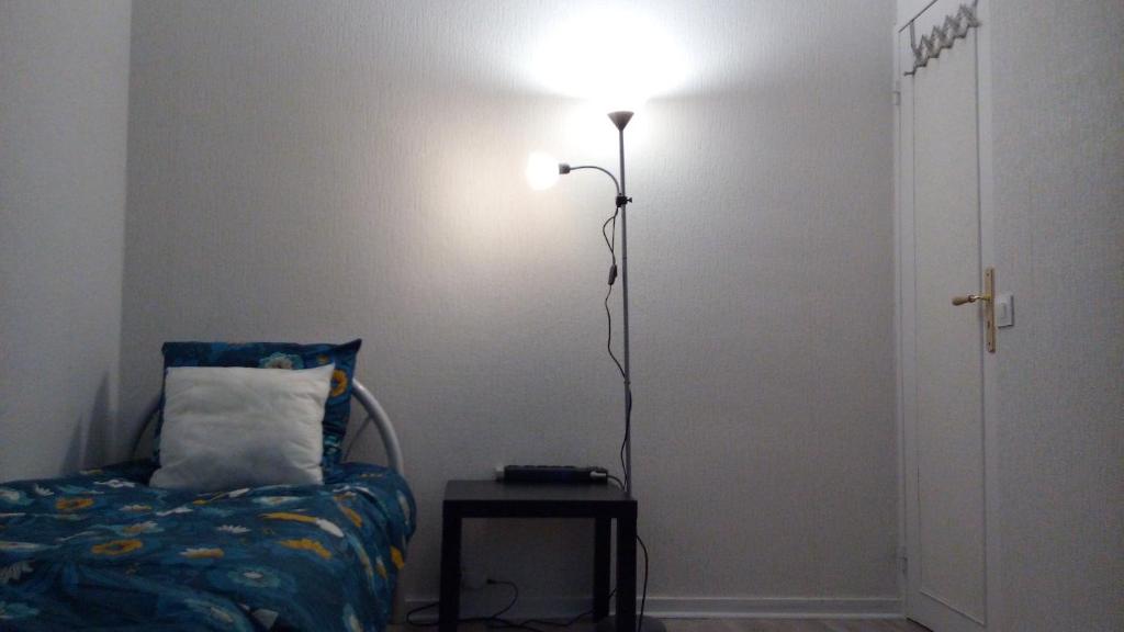 a lamp in a room with a bed and a table at chambre lits jumeaux in Chevilly-Larue