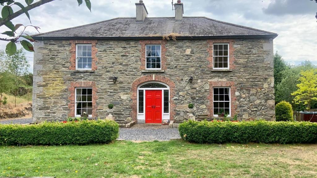 una vieja casa de piedra con una puerta roja en Lacken Millhouse and Gardens, en Cavan