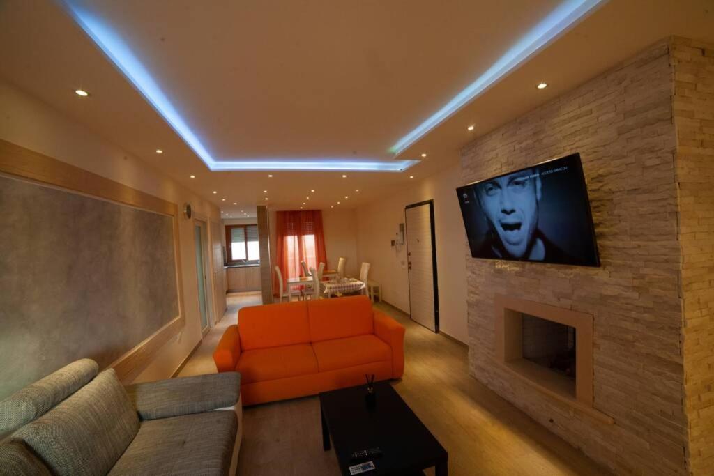 sala de estar con sofá naranja y TV en una pared de ladrillo en B&b Miramare Taranto, en Taranto