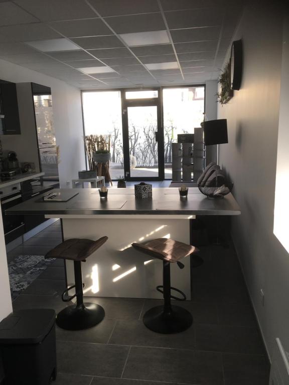 een keuken met een grote tafel en 2 krukken bij L’appartement charmant in Dole